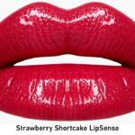 Close-up of glossy bright red lips, product branding 'Strawberry Shortcake LipSense' visible below.